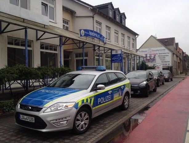 Die Polizei sichert den Brandort am Roßlauer Luchplatz. Die Brandschäden sind im hinteren Teil des Wohn- und Geschäftshauses zu sehen.