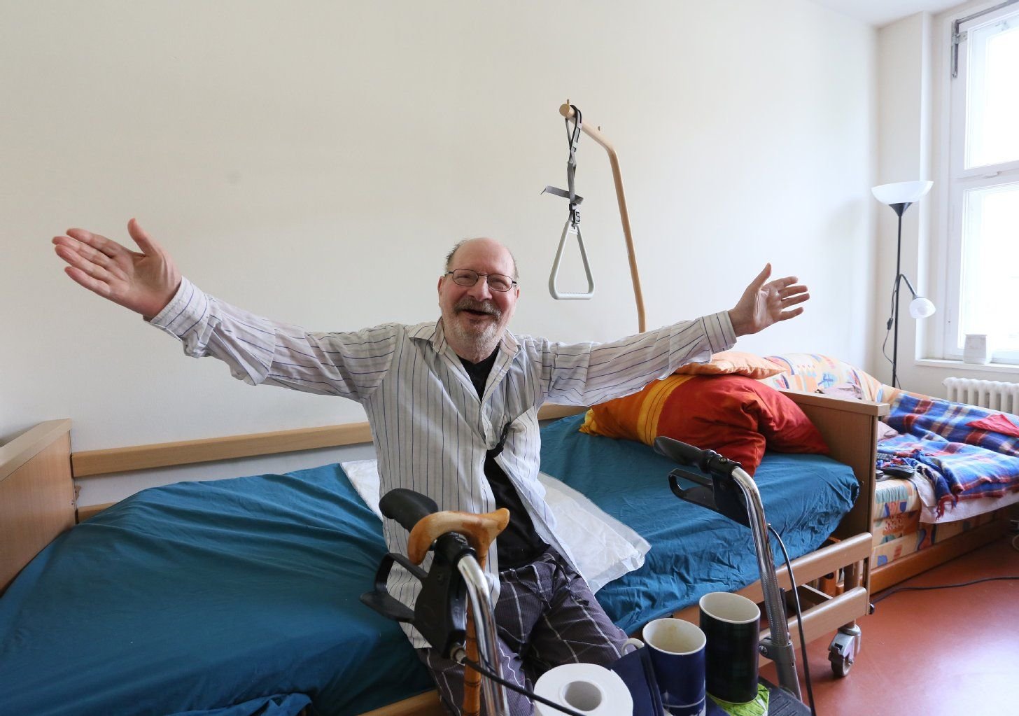 Mit ausgebreiteten Armen sitzt Hans-Heinrich in seinem Zimmer in der Wohngemeinschaft für homosexuelle Senioren in Berlin.