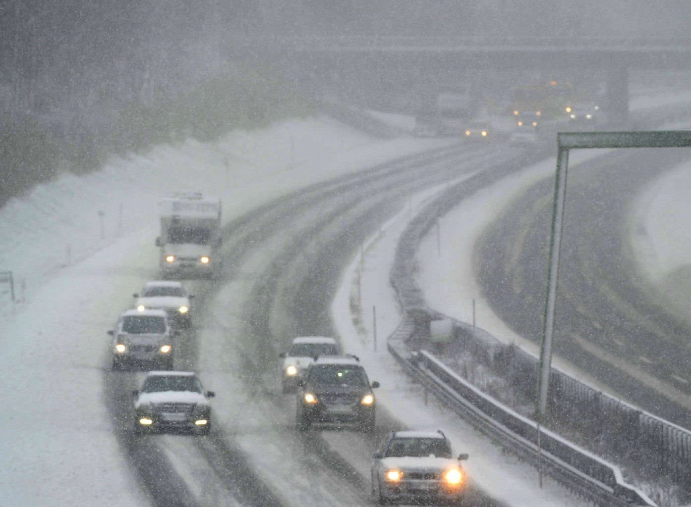 Autos fahren über die zugeschneite Fahrbahn einer Autobahn. Am Donnerstag kam wegen Glätte und Schnee bereits zu zahlreichen Unfällen.
