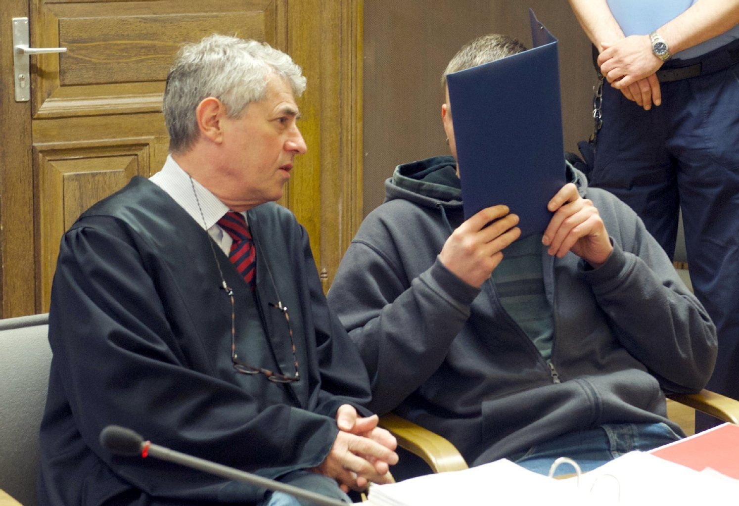 Der Angeklagte Mike G. verdeckt sein Gesicht im Landgericht in Leipzig, links neben ihm sitzt sein Anwalt Stephan Bonell.