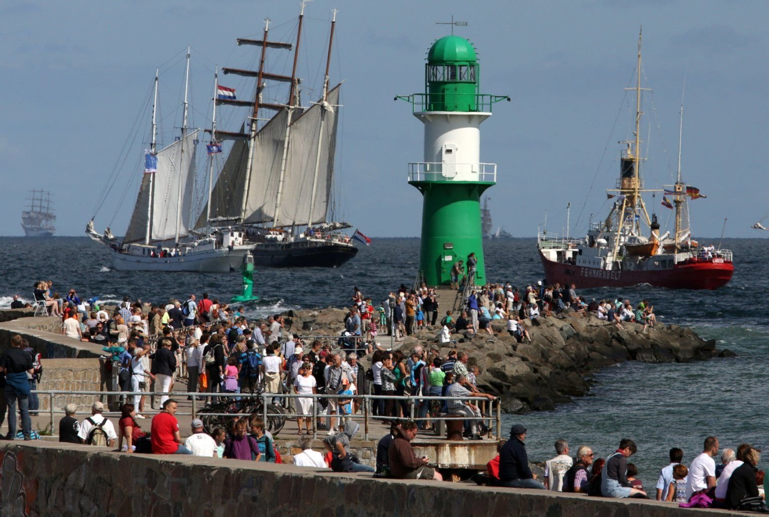 Segelschiffe der 23. Hanse Sail fahren an der Mole in Warnemünde vorbei auf die Ostsee hinaus.