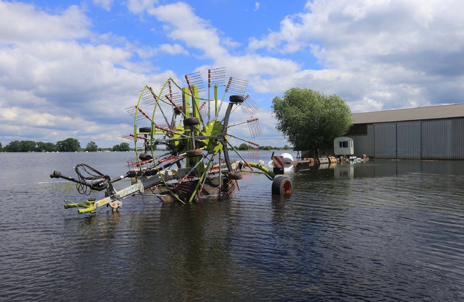 Ein Heuwender steht auf einem vom Hochwasser der Elbe überfluteten Bauernhof in Schönhausen (Sachsen-Anhalt).