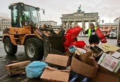 Männer räumen am Samstag (01.01.2004) den Müll vor dem Brandenburger Tor in Berlin zusammen. Tonnenweise Müll sind Hinterlassenschaften der größten Silvesterfeier in Deutschland. (Foto: dpa)