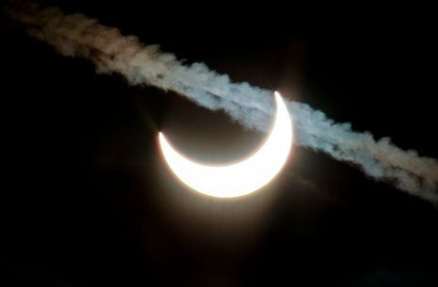 Der Mond verdeckt einen Teil der Sonne am verschleierten Himmel über dem Großen Feldberg nördlich von Frankfurt am Main und formt sie zur Sichel, während im Vordergrund ein Kondensstreifen vorbei zieht. (FOTO: DPA)