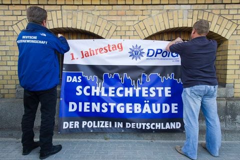 Zwei Mitglieder der Deutschen Polizeigewerkschaft (DPolG) befestigen am Freitag in Magdeburg am Gebäude des Polizeireviers Magdeburg ein Plakat mit der Aufschrift «1. Jahrestag - Das schlechteste Dienstgebäude der Polizei in Deutschland». (FOTO: DAPD)