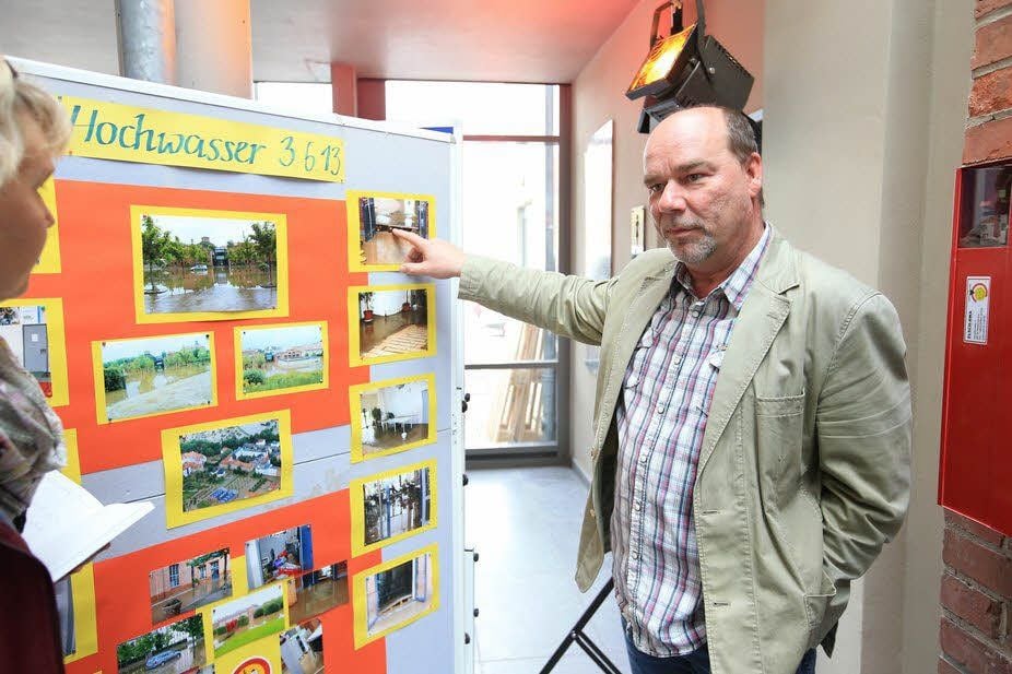 Vereinschef Silvio Klawonn zeigt anhand der aufgebauten Fotodokumentation, wo das Wasser im Juni vergangenen Jahres gestanden hat.