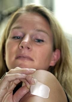 Kerstin Aschoff klebt sich zu Demonstrationszwecken am Dienstag (12.08.2003) in Hamburg ein Verhütungspflaster auf die Schulter. (Foto: dpa)