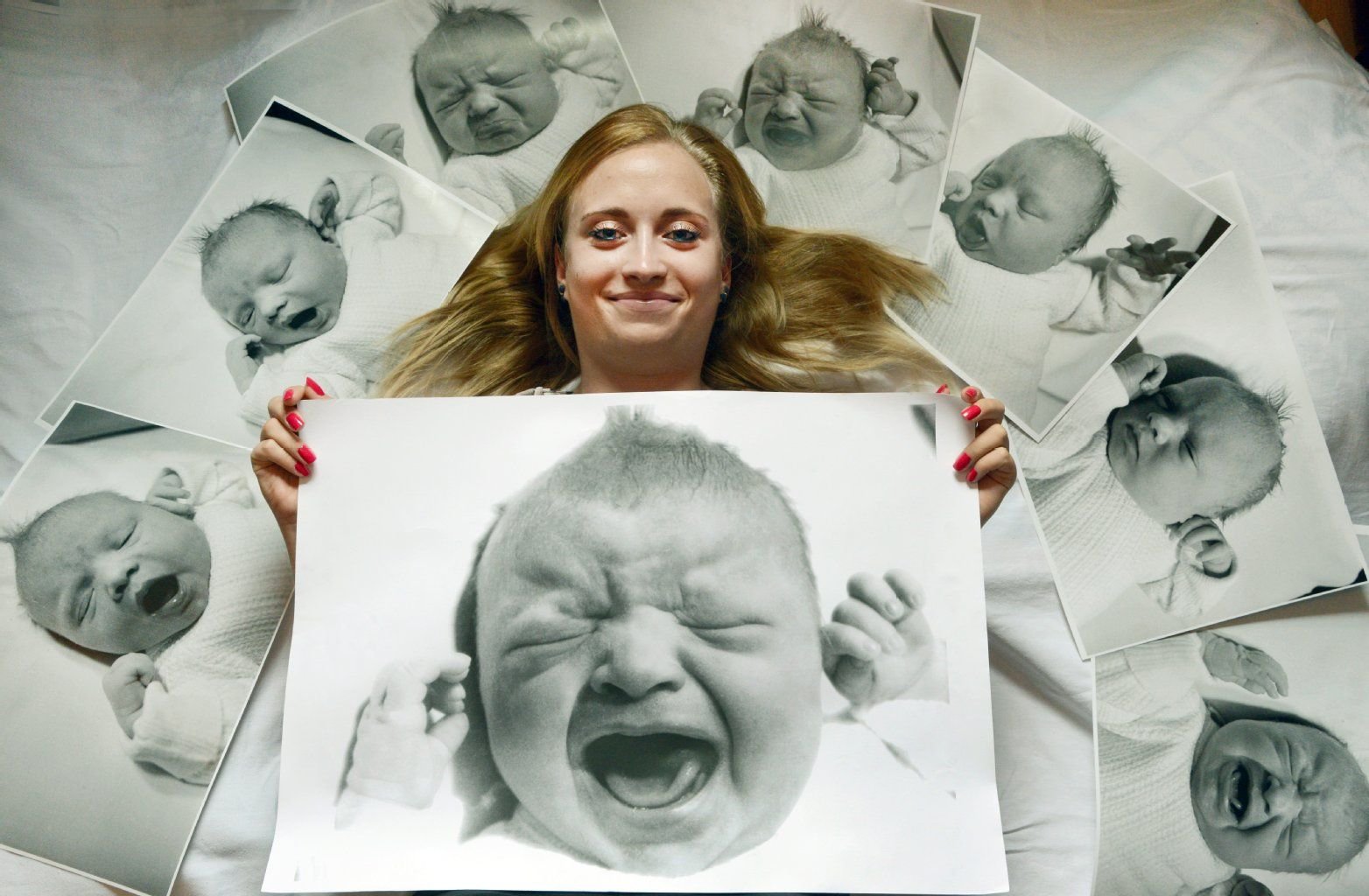 Lachend liegt Sarah Klier, die als letztes DDR-Baby weltbekannt wurde, inmitten ihrer Babyfotos in ihrem Heimatort Borsdorf bei Leipzig.