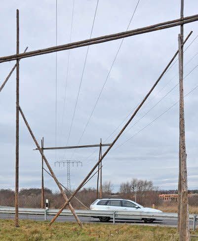 Tore aus Holz stehen zum Schutz unter der Freileitung.