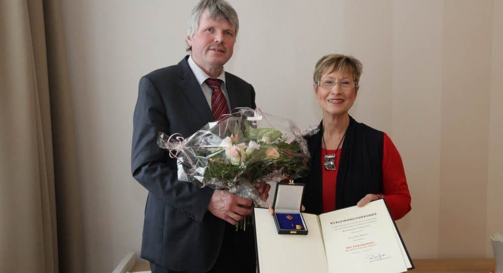 Heide Reinsch zeigt die Urkunde und Ehrennadel des Landes Sachsen-Anhalt, die sie von Landrat Martin Skiebe (links) überreicht bekommen hat.