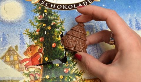 Eine Frau nimmt für eine Fotoillustration ein Stück Schokolade aus einem Schokoladenweihnachtskalender der Firma Rausch. Die Stiftung Warentest hat in der Schokolade von 24 Adventskalendern für Kinder Rückstände von Mineralöl und ähnlichen Substanzen nachgewiesen. (FOTO: DAPD)