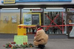 Eine Frau legt in Berlin vor einer Supermarktfiliale in Berlin-Reinickendorf, Ortsteil Konradshöhe, Blumen nieder. In der Nacht war bei einem Überfall ein 20 Jahre alter Wachmann getötet worden. (Foto: dpa)