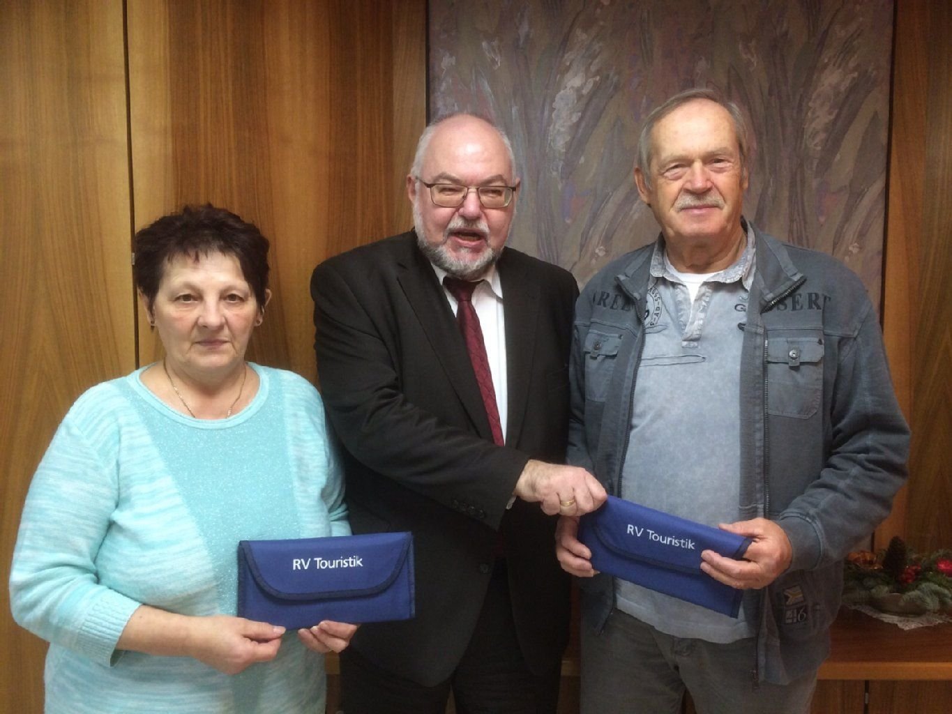 Manfred Bähr, Vorstandsvorsitzender der Volksbank Dessau-Anhalt (m.), überreicht den Gewinnern Eva Berndt und Dieter Hilse die Reisegutscheine.