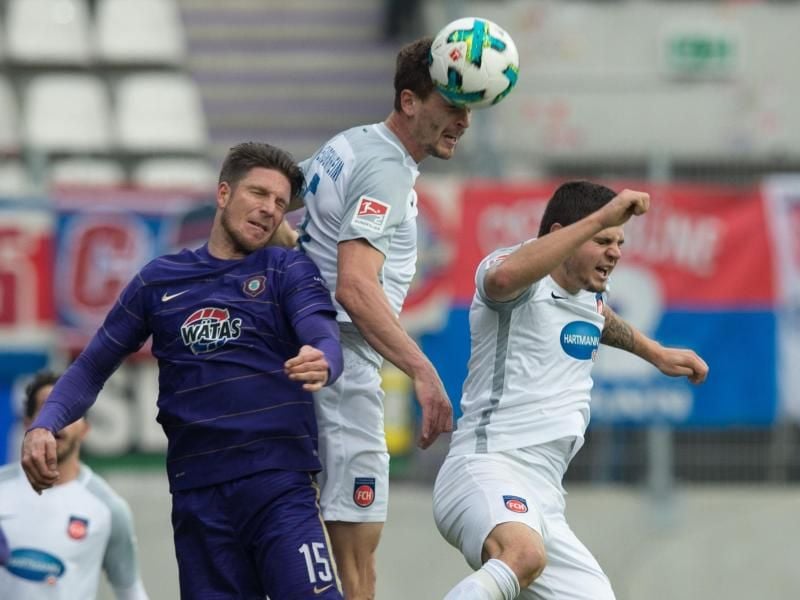 Aues Dennis Kempe (l) im Kopfballduell mit Heidenheims Mathias Wittek (M) und Marnon Busch. Foto: Sebastian Kahnert