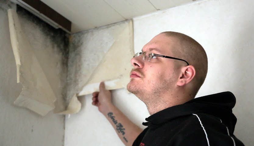 David Richter zeigt in Plossig eine Schimmelecke im Wohnzimmer.