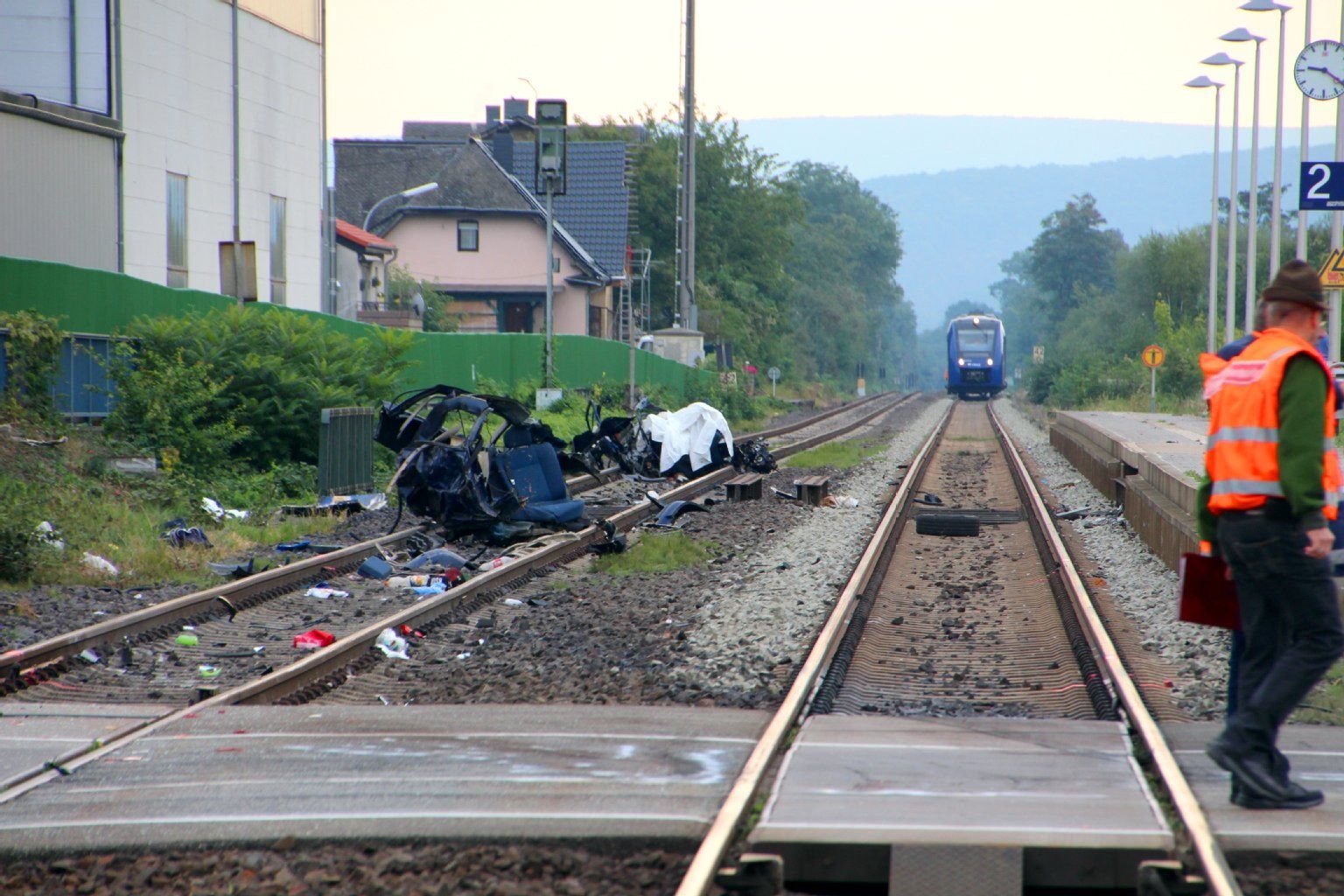 Das Wrack eines Autos liegt am Samstag auf den Gleisen in der Nähe eines Bahnübergangs in Monzingen (Rheinland-Pfalz). Im Hintergrund steht der Zug, der das Auto erfasst hatte.
