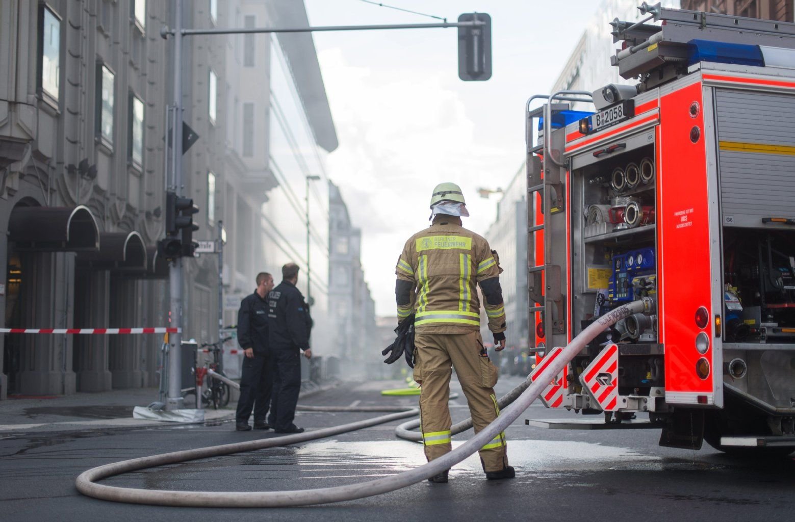 Einsatzkräfte der Feuerwehr stehen vor dem Kaufhaus Galeries Lafayette.