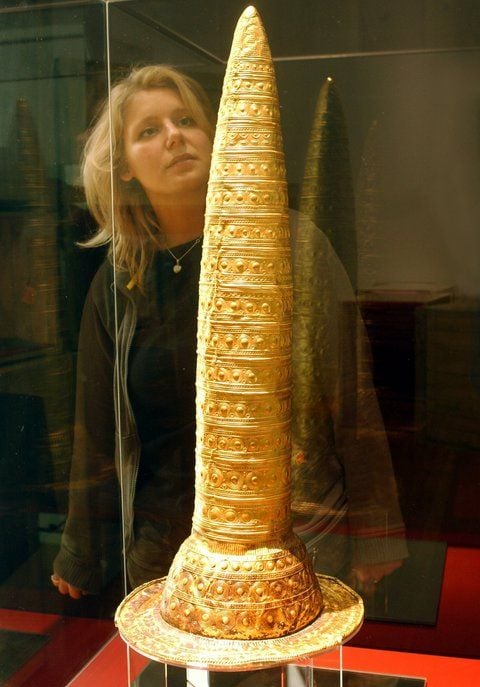 Den Berliner Goldhut, eine über 3000 Jahre alte, papierdünne Kopfbedeckung eines Priesters aus Europa, betrachtet eine Besucherin im Martin-Gropius-Bau in Berlin. (ARCHIVFOTO: DPA)