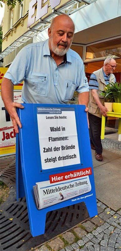 Detlef Böttcher vom Zeitungskiosk stellt die Aufsteller raus.