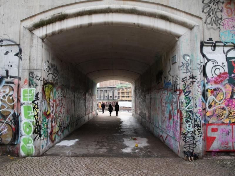 Menschen gehen durch die Unterführung zum Monbijoupark in Berlin-Mitte, in der Unbekannte eine Rose und eine Kerze abgelegt haben. Der 13-Jährige war hier bei einem Streit tödlich verletzt worden. Foto: Paul Zinken/dpa