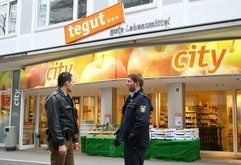 Zwei Polizisten stehen in Darmstadt vor einem Supermarkt der Kette «tegut». Eine Geiselnahme in dem Darmstädter Supermarkt war am Freitag nach gut 90 Minuten zu Ende gegangen. (Foto: dpa)