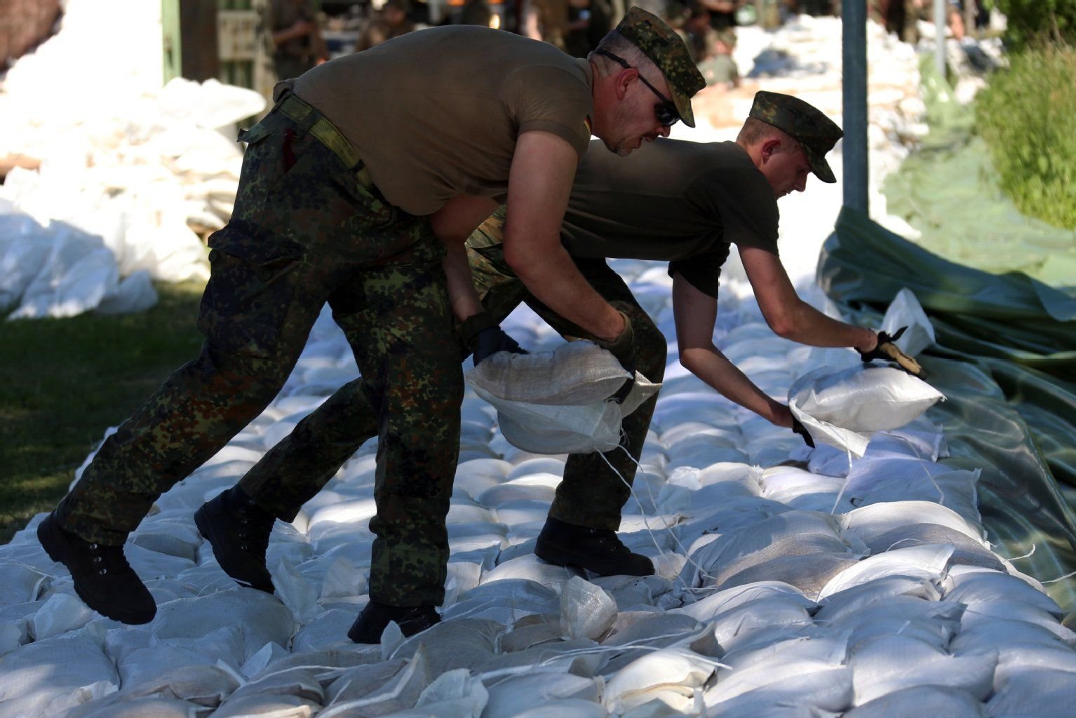 Bundeswehrsoldaten arbeiten aus einem Schutzwall aus Sandsäcken.