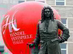 Hinter dem Denkmal für den Komponisten Georg-Friedrich Händel schwebt am Mittwoch (02.06.2004) auf dem Marktplatz in Halle (Saale) ein Ballon mit dem Schriftzug "Händelfestspiele Halle". Halle ist Sachsen-Anhalts Bewerber um dieKulturhauptstadt Europas im Jahre 2010. (Foto: dpa)
