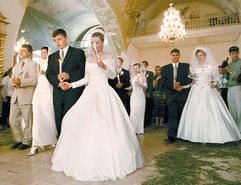 Kerzen tragende Brautpaare nehmen in der Auferstehungskirche in Moskau an einer Massenhochzeit teil. (Foto: dpa)