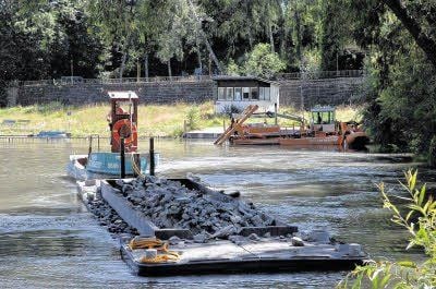 Die Schute wird mit dem Gestein beladen und fährt damit auf den See, dort werden die Steine dann in das Wasser gelassen.