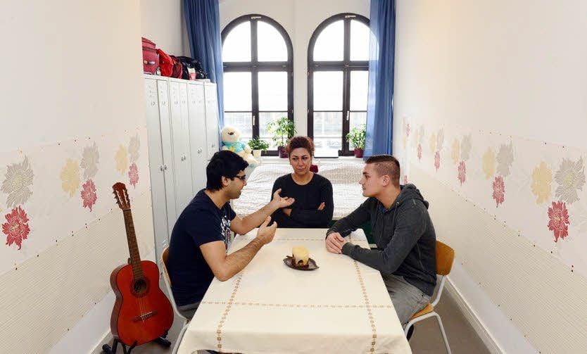 Stippvisite bei den Nachbarn: David und Rebecca unterhalten sich in der Asylbewerberunterkunft mit Sozialarbeiter Dennis Hönig (re.).