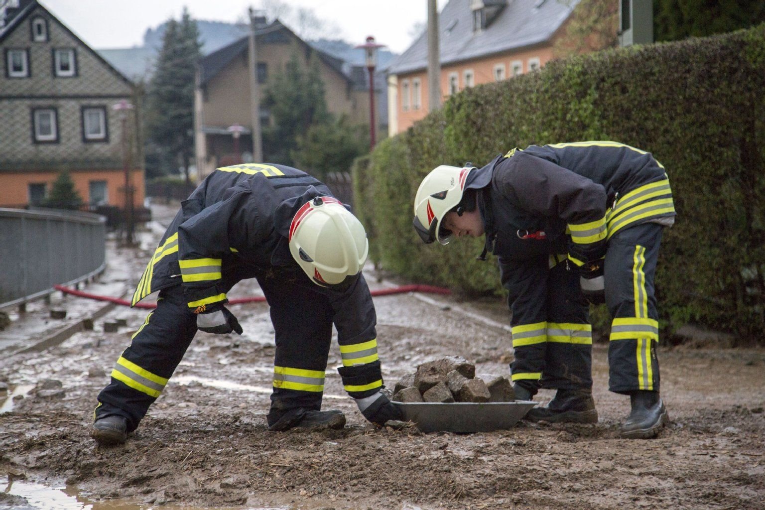 Feuerwehrleute beseitigen in Raschau die Reste einer Schlammlawine. Schlamm und Geröll waren nach starkem Regen in das Tal gerutscht.