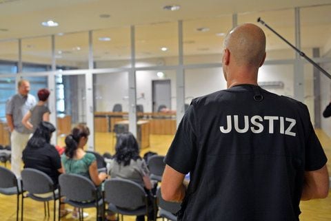Ein Justizbeamter steht neben Zuschauern im Landgericht Halle. Geldbußen müssen zum Beispiel bezahlt werden, wenn ein Staatsanwalt ein Verfahren vorläufig einstellt oder ein Gericht eine Strafe zur Bewährung aussetzt. (ARCHIVFOTO: DPA)