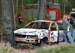 Vor dem in einem Wald in Celle ausgebrannt gefundenen Auto stehen am Dienstagabend (7. Juni 2005) ermittelnde Polizisten. In dem VW-Passat verbrannten ein vater und seine beiden Söhne. (Foto: dpa)