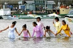 Vietnamesinnen in traditionellen Gewändern gehen zum internationalen Elbe-Badetag am Sonntag (17. Juli 2005) in der Dresdner Innenstadt in die Elbe. (Foto: dpa)