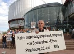 Gerhard Anders, Mitglied des «Vereins gegen die Abwicklung der Bodenreform», hält am Donnerstag (30.06.2005) vor dem Europäischen Gerichtshof für Menschenrechte ein Plakat mit der Aufschrift «Keine entschädigungslose Enteignung von Bodenreform-Erben» in Händen. (Foto: dpa)
