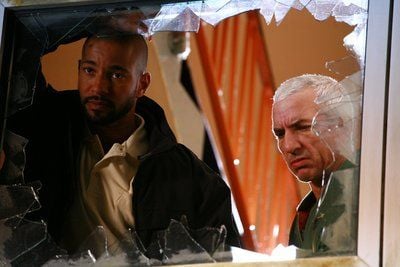 Die Polizisten Philipp (Tyron Ricketts, links) und Ron (Ralf Richter) stehen in einer Szene aus dem Film «Kopf oder Zahl» hinter einer gesplitterten Fensterscheibe. (FOTO: DPA)