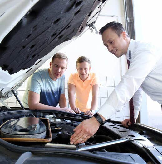 BMW-Mitarbeiter Carsten Becker (r.) erklärt Marius Dannenberg (l.) und Jonas Backhaus (r.) die Funktionsweisen eines Pkws.