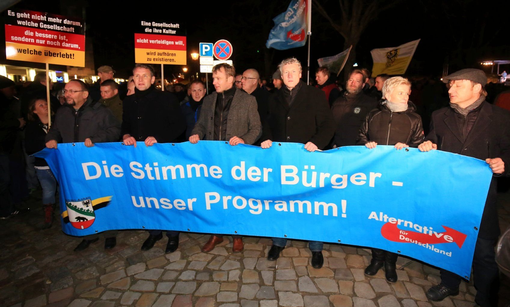 Björn Höcke (2.v.l.), Vorsitzender der AfD-Fraktion im Thüringer Landtag, und der Landesvorsitzende der Partei "Alternative für Deutschland" (AfD) von Sachsen-Anhalt, Andre Poggenburg (M), gehen mit einem Plakat am 27.01.2016 auf einer Kundgebung der Partei in Magdeburg über den Domplatz.