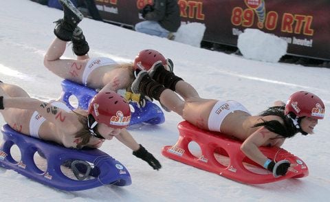 Nacktrodlerinnen fahren beim traditionellen Nacktrodeln in Braunlage auf Schlitten die Piste hinunter. (FOTO: DAPD/ARCHIV)