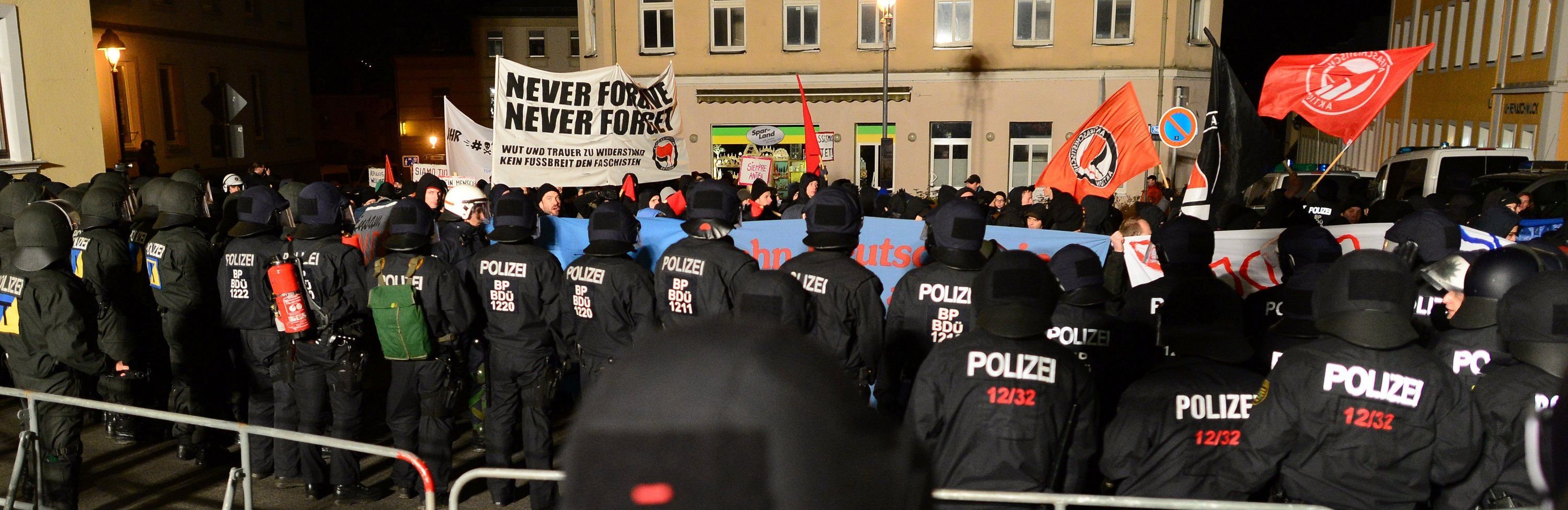 Teilnehmer einer Antifa-Kundgebung protestieren hinter einer Polizeikette in Schneeberg.
