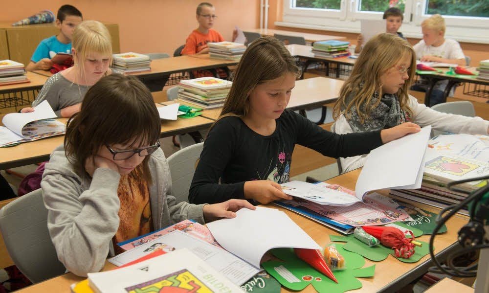 Die erste Stunde in der neuen Schule. Annika, Angelina und Sophie (v.l.) aus der ersten Reihe schauen sich ihre neuen Lernmaterialien an.