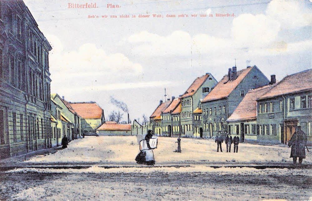 Die Karte mit dem Bitterfeld-Spruch zeigt den Plan um 1905 von der Mühlstraße aus. Vorn links das Haus steht noch, von den rechten Gebäuden sind nur das vierte und fünfte von rechts erhalten.