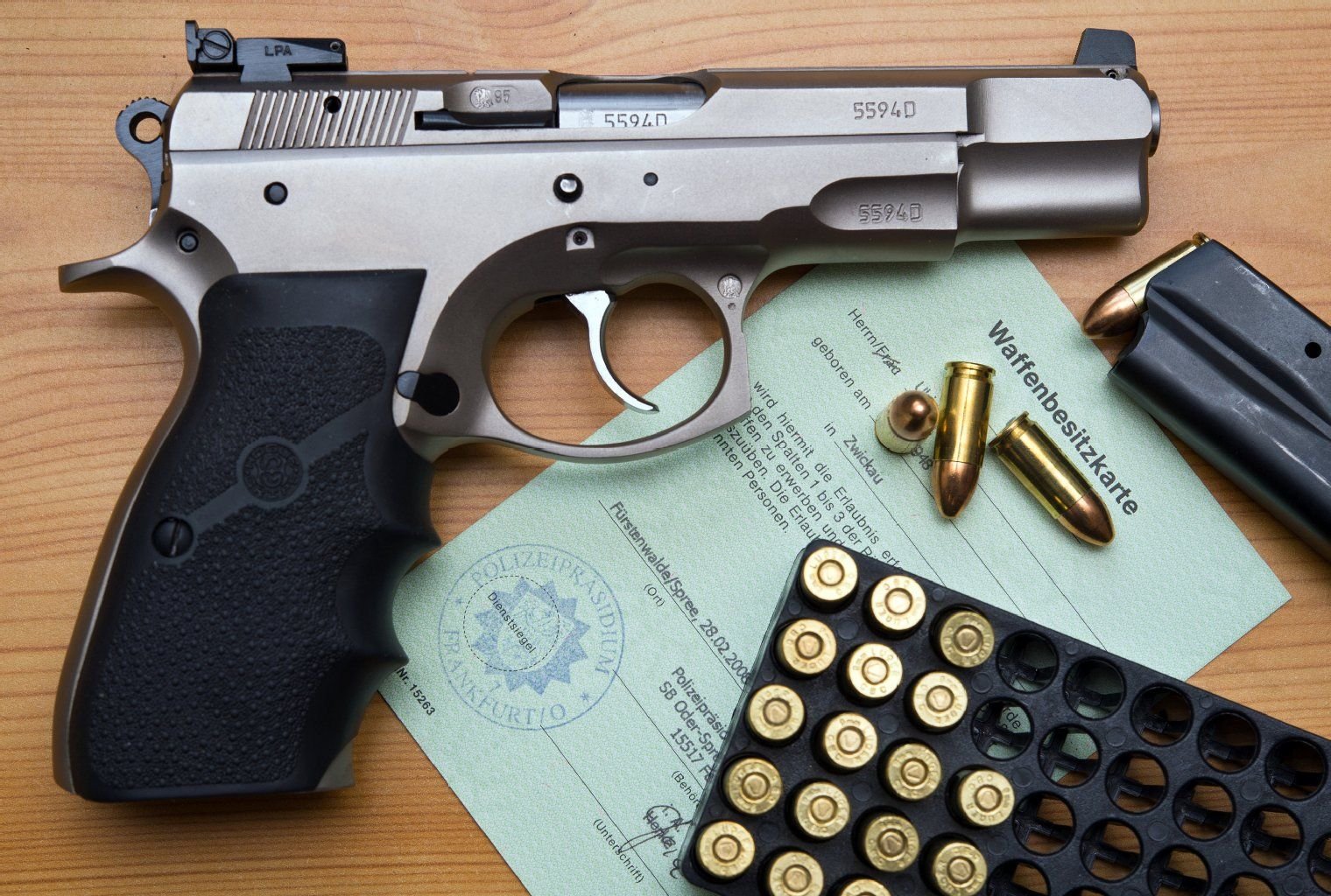 Eine Kaliber 9 mm Pistole, Patronen und ein Magazin liegen auf einer Waffenbesitzkarte.