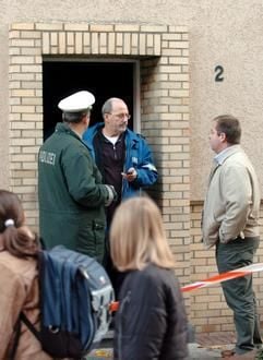 Polizei- und Kriminalbeamte stehen am Donnerstagmorgen am Eingang des Brandhauses in der Grünstraße in Jülich im Kreis Düren (Nordrhein-Westfalen). (Foto: dpa)