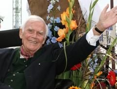 Der Schauspieler Joachim Fuchsberger winkt auf prächtig geschmückten Wagen als Gast beim Einzug der Wiesn-Wirte zum Oktoberfest in München. (Foto: dpa)