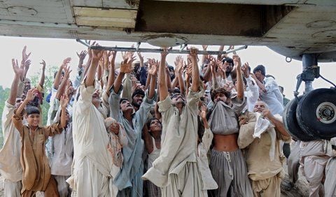 Verzweifelte Menschen hängen sich an die Kufe eines Armee-Hubschraubers, der am 7. August nahe der Ortschaft Muzaffargarh in der Punjab-Provinz unterwegs war. (FOTO: DPA)