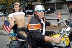 Eine Mitfahrerin entbößt ihre Brust, während der Fahrer eines Harley-Davidson-Motorrades über die zum Teil extra abgesperrte Reeperbahn in Hamburg während einer dreitägigen Party zum 100-jährigen Bestehen des amerikanischen Motorradbauers im Juli 2003 rollt. (Archivfoto: dpa)