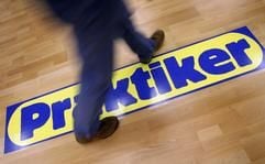 Ein Mann geht am Montag (07.11.2005) in Frankfurt vor Beginn einer Pressekonferenz über das Logo der Baumarktkette Praktiker, das auf dem Parkett klebt. (Foto: dpa)