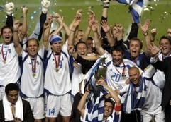 Die griechischen Spieler um Mannschaftskapitän Theodoros Zagorakis (M) jubeln mit der EM-Trophäe über ihren Sieg im EM-Fianle. Griechenland gewinnt mit 1:0 und wird erstmals Europameister. (Foto: dpa)