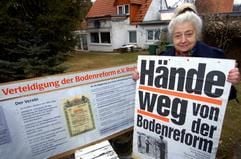 Die Rostockerin Margot Hein zeigt ein Protestplakat gegen die Enteignung von Bodenreformland nach der Deutschen Einheit. Die Ehrenvorsitzende des «Vereins zur Rettung der Bodenreform» kämpft um ein mittlerweile mit Einfamilienhäusern bebautes acht Hektar großes Grundstück am Stadtrand der Hansestadt, das sie als Bodenreformland von ihrem Vater geerbt hatte. (Foto: dpa)
